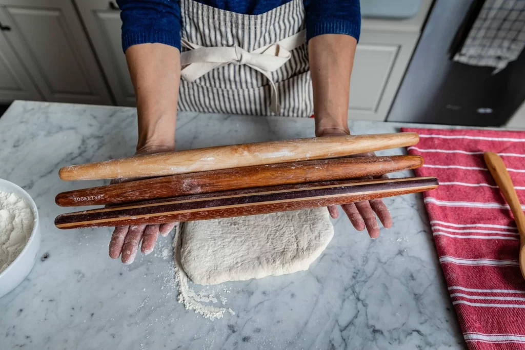 woman holding 3 tapered french rolling pins 