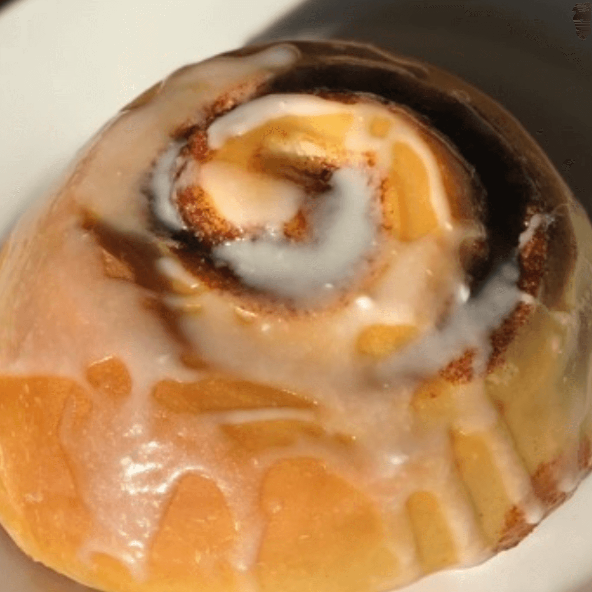 vanilla glaze iced sourdough cinnamon roll on a white plate