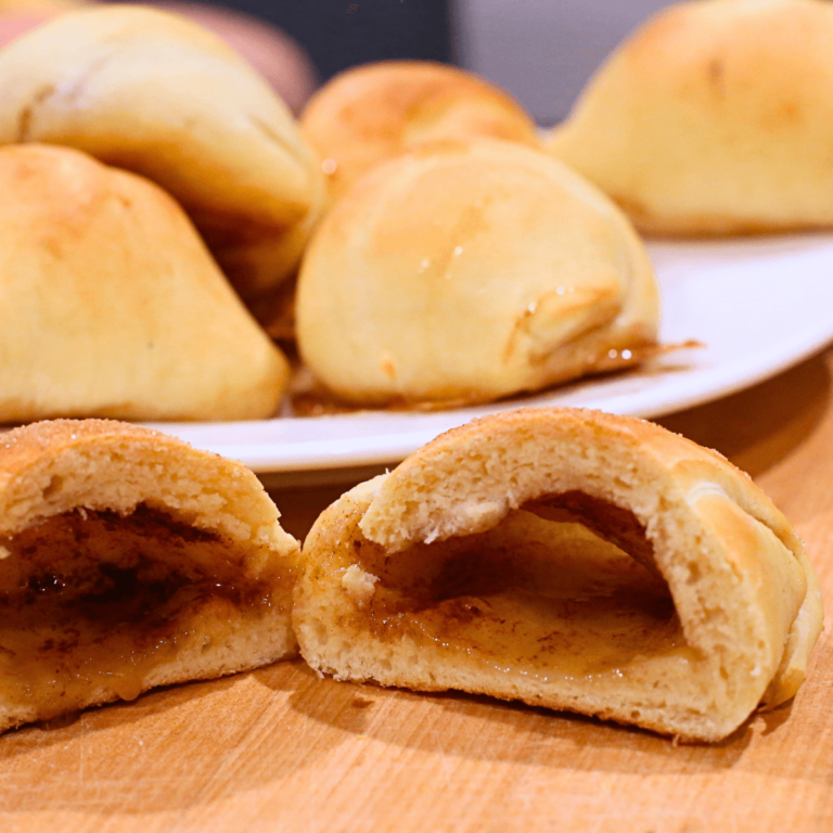 Sourdough Resurrection Roll cut open in foreground showing the empty opening that resembles the empty tomb of Jesus Christ for easter sunday, plate of rolls in the background