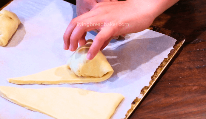 child's hand rolling the dough coated marshmallow up the rest of the dough to make sourdough resurrection rolls