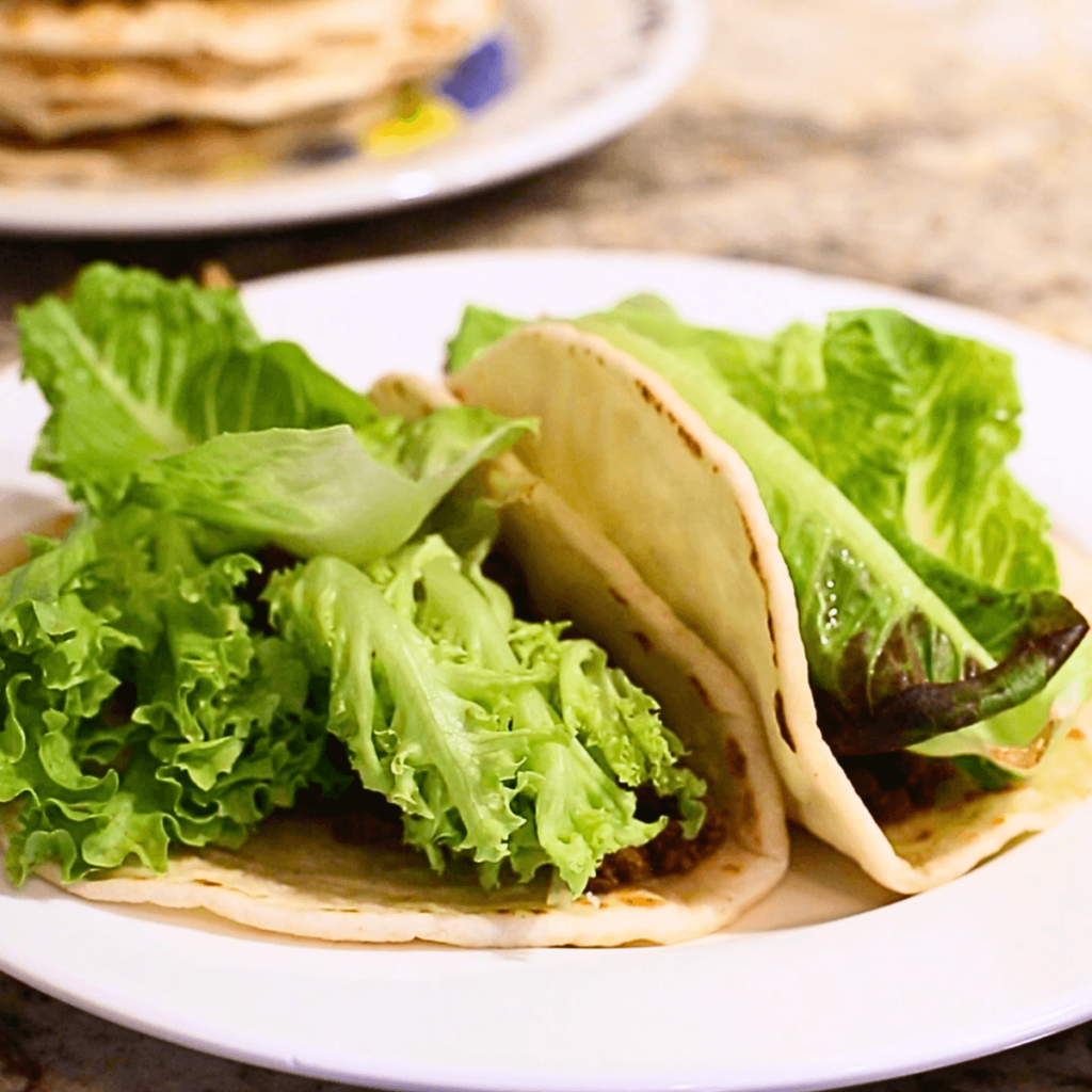 stack of sourdough tortillas made with a tortilla press for an easy dinner, for instance tacos like the two pictured on this white plate