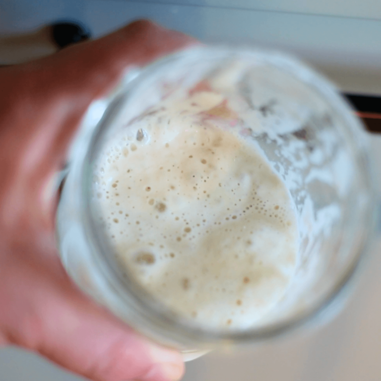 bubbly active sourdough starter ready to use in a glass jar, top view