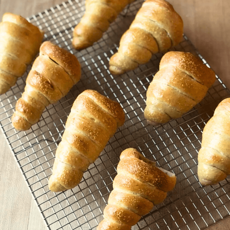 eight Sourdough Cone-Shaped Rolls lined up on a wire cooling rack
