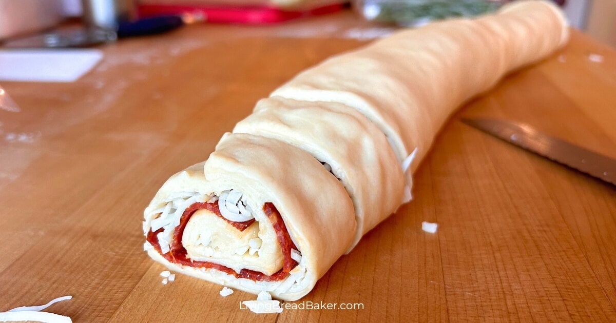 easy sourdough pizza rolls with dough into a log with cheese and pepperonis in the layers with two sections cut with bread knife